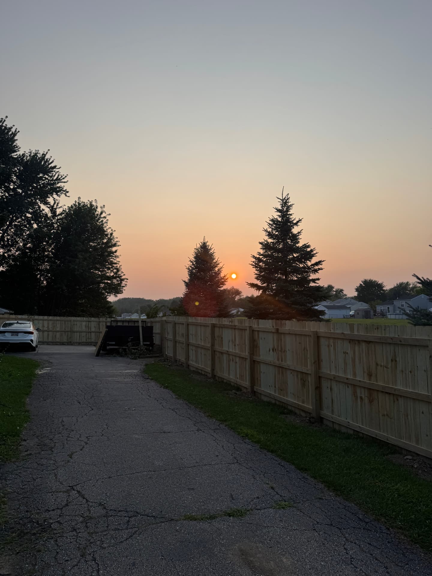 New wood privacy fence installed by HPC along a driveway at sunset in the Toledo area